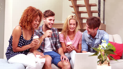 smiling friends drinking coffee and using laptop