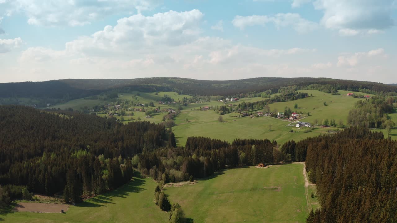 Drone shot of czech highlands village surrounded with spruce forest