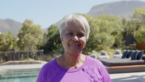 portrait of happy senior biracial woman smiling in sunny garden, unaltered, in slow motion