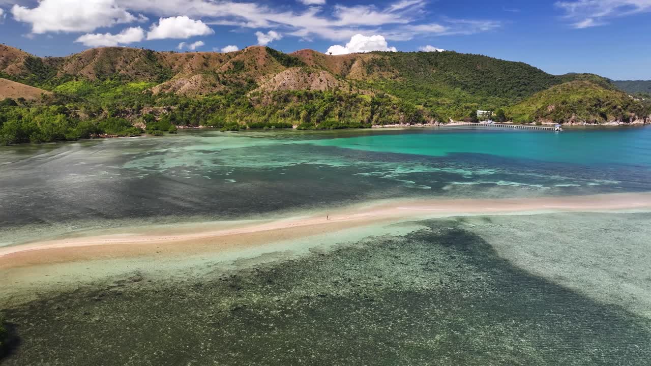Lone traveler walking on sand strip between islands, exotic Palawan, Philippines, drone