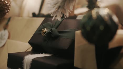 present or gift wrapped with black wrapping paper and green ribbon with a bell underneath a christmas tree