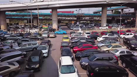 Congested-Car-Park,-between-a-Main-Road-covered-in-Traffic-and-an-Empty-Wasteland,-Bangkok,-Thailand