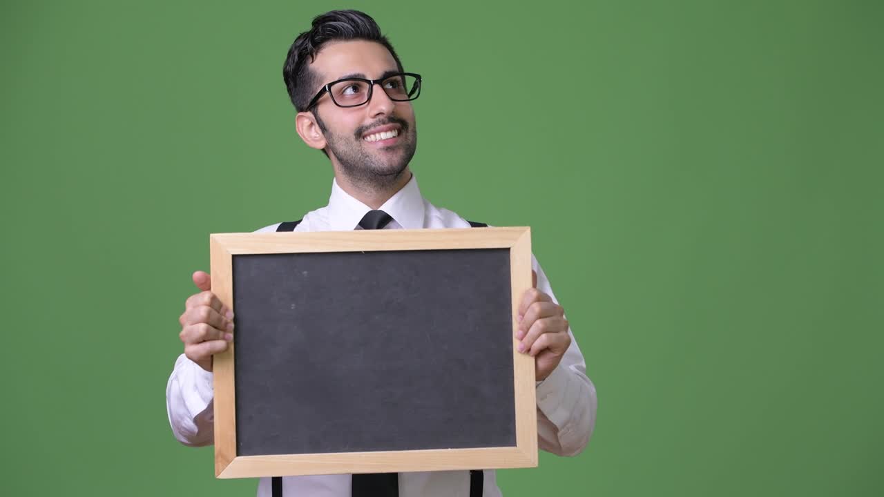 joven empresario persa barbudo y guapo contra un fondo verde