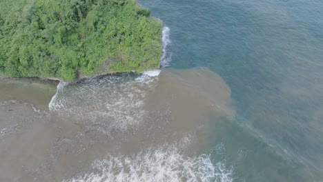 top down aerial drone shot over polluted sewage water and floating trash with debris over dead coral reef mixing with turquoise water and tropical coastine in bali indonesia