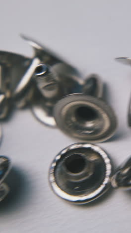 motion above scattered shiny metal rivets lying on clean white background extreme close view
