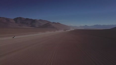 aerial shot of vehicles traversing through the salvador dalí desert in bolivia