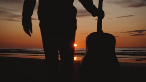 man running with guitar in back sand beach at sunset-2