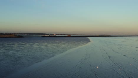 birds-eye-view-of-ocean-during-low-tide-in-Dublin,-Ireland-at-sunset