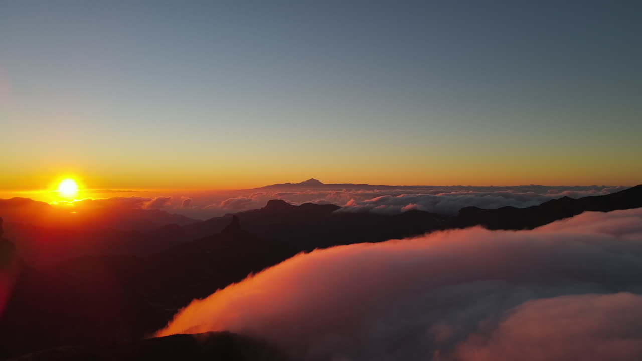 Flying between clouds and the Teide volcano on the island of Gran Canaria during a magical sunset