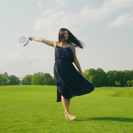 A-Stylish-Pregnant-Woman-In-A-Light-Dress-Carefree-Walks-Along-A-Green-Meadow-Past-The-Camera