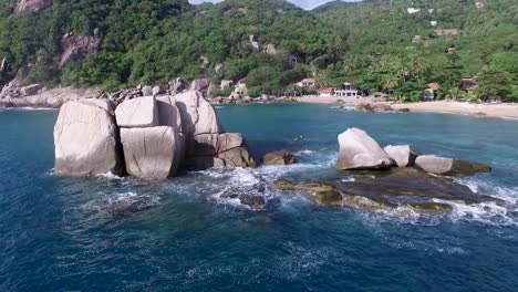 waves hitting rocks drone pan left palm tree sandy beach background