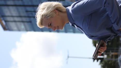 a businesswoman holding her phone with her hands waiting to cross the roadway