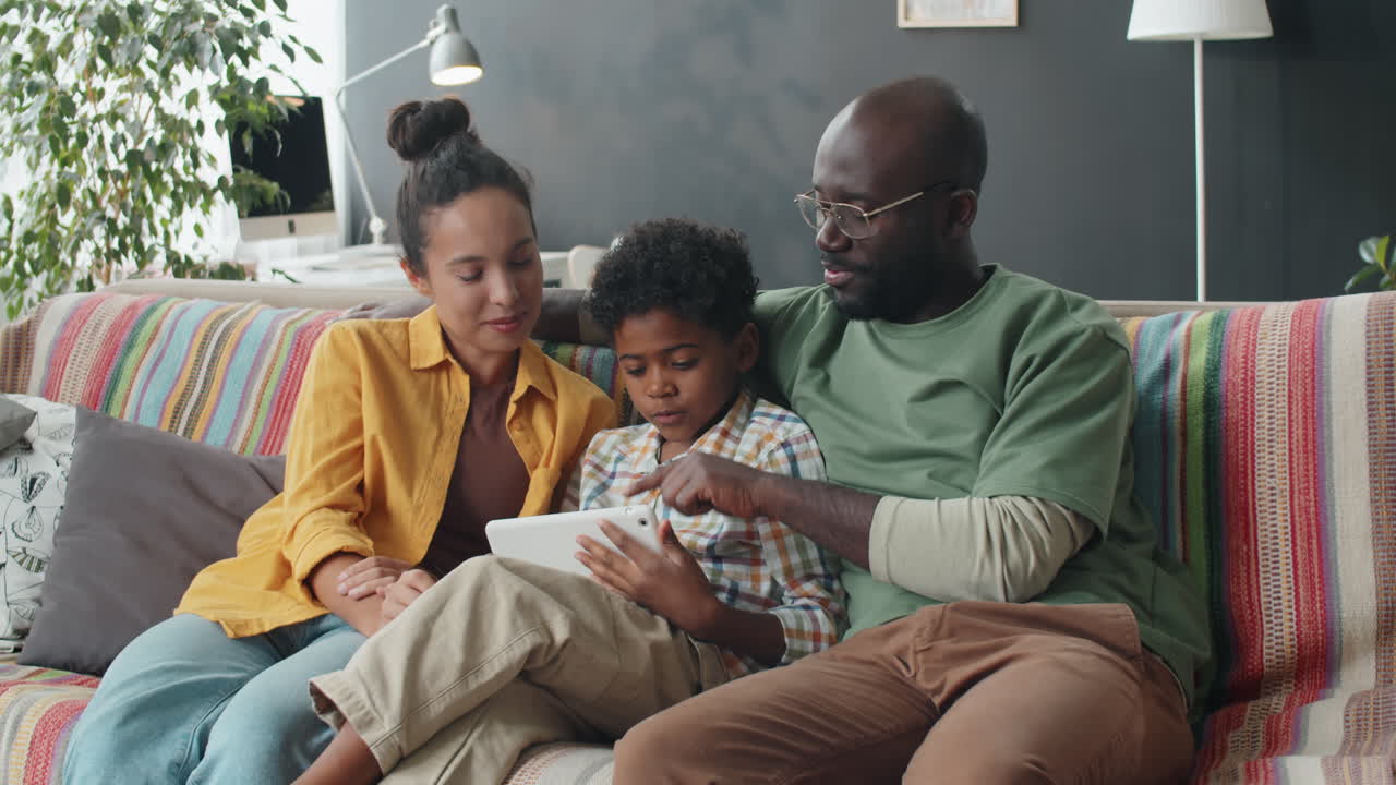 Famiglia afroamericana allegra che usa un tablet digitale sul divano a casa