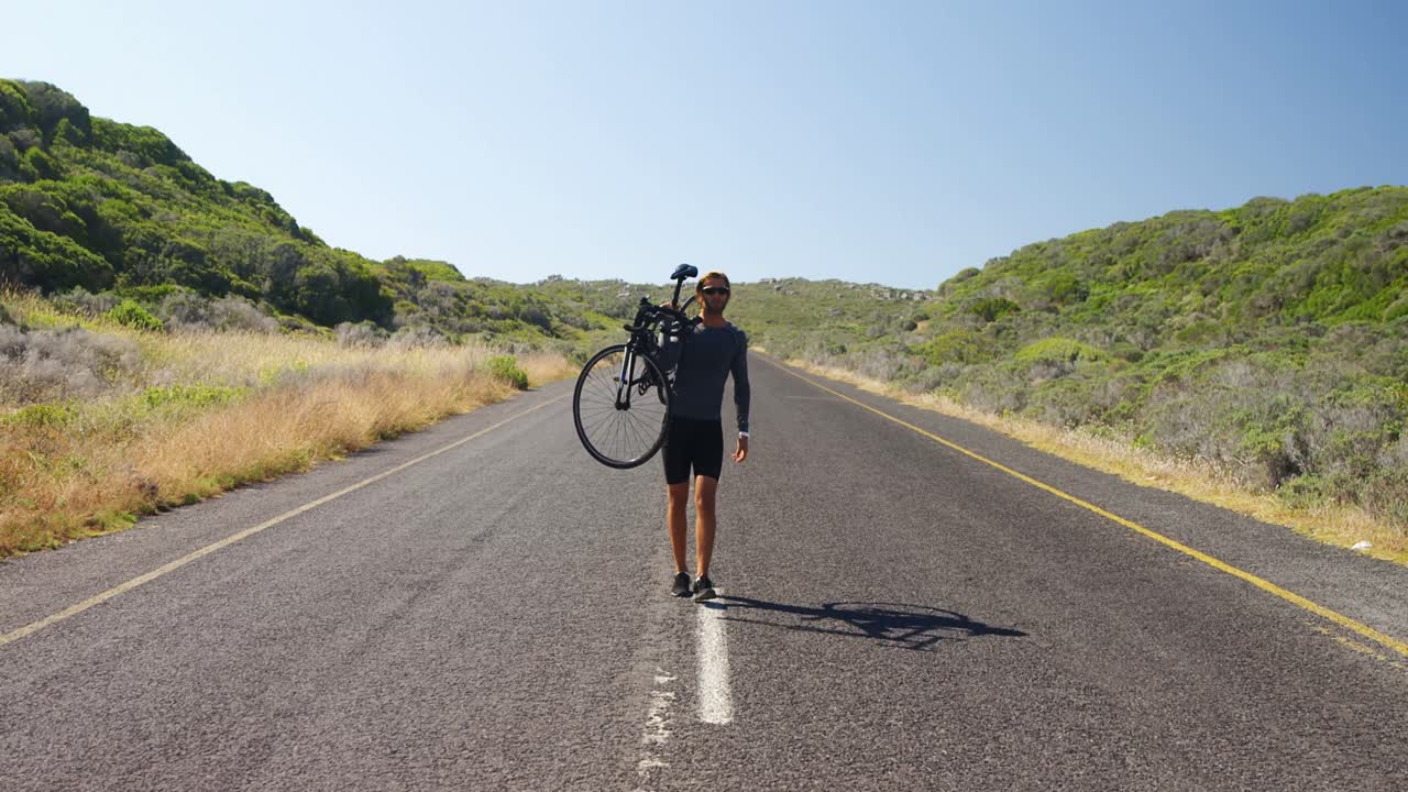 시골 도로 에서 자전거 를 운반 하는 트라이애슬리트 남자