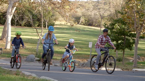 panning shot following family cycling together in a park