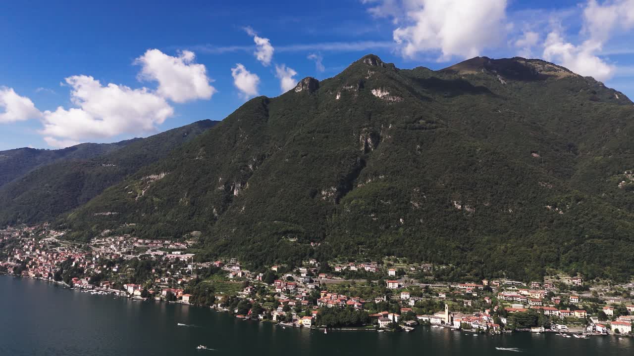 Fly sideways over Lake Como, view of green mountain, blue sky and some clouds