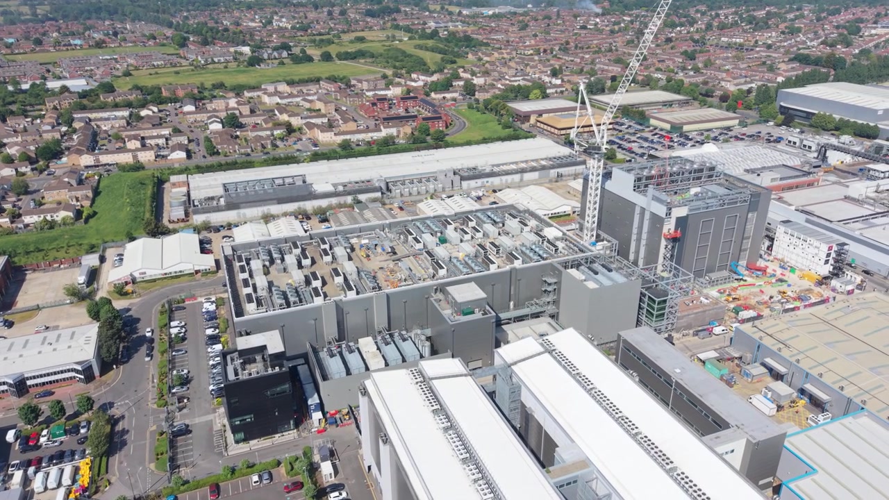 Un grande complesso di data center è in costruzione, caratterizzato da più edifici moderni e una gru operativa.