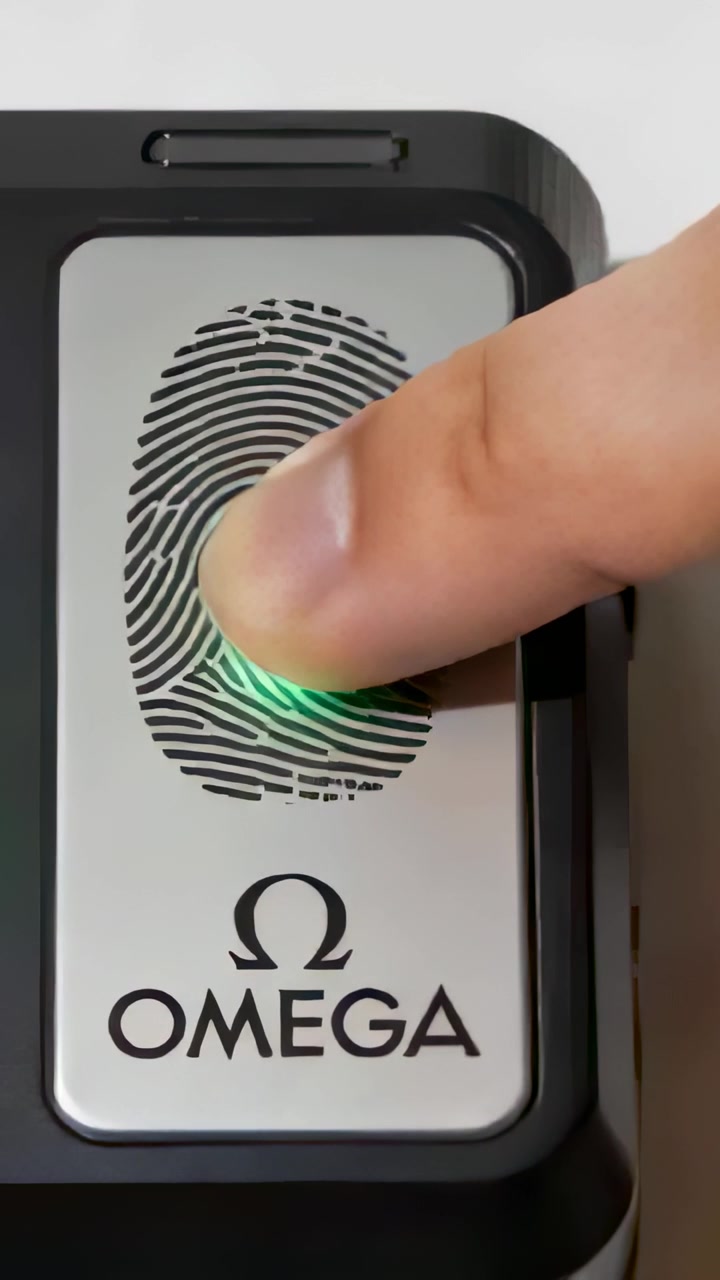 Vertical video: Pressing finger activating reader on table, green glow, Omega mark visible for scan