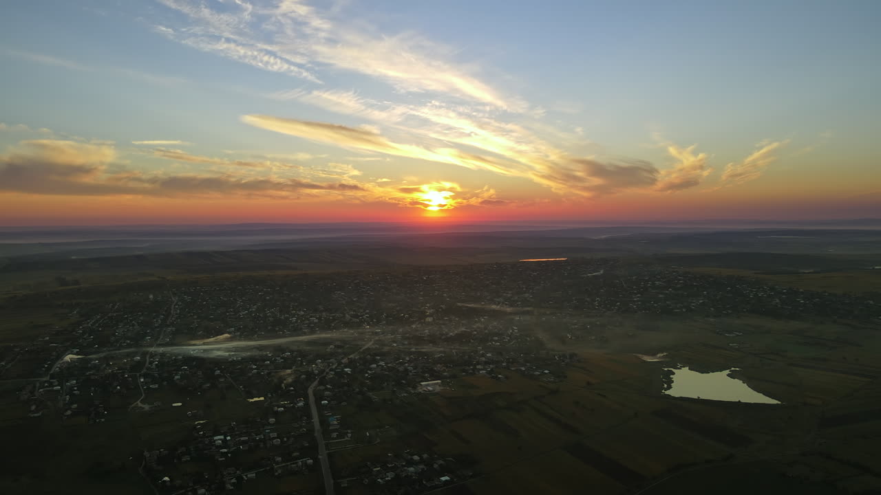 Aerial drone view of village in Moldova at sunset. Few columns of smoke from fires, wide fields