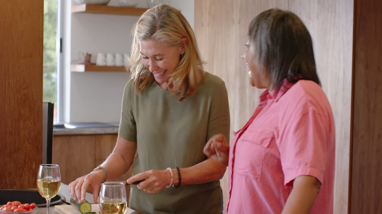 Preparing food and enjoying conversation, multiracial female friends spending time together, at home