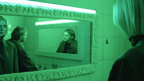 mujer y hombre mirando en los espejos en el baño con luz verde