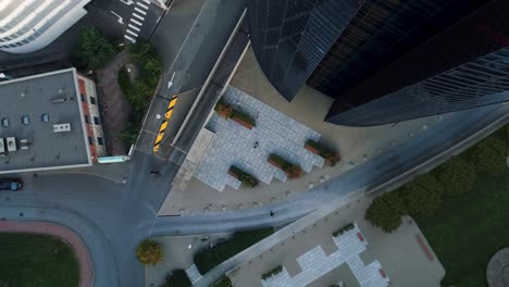 big city businesswoman uses laptop computer during lunch break in concrete urban park. manager goes through commercial and financial projects. top-down zoom out aerial drone shot.