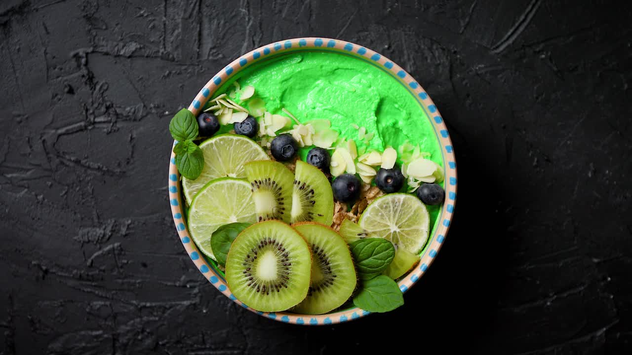 Groene smoothie of yoghurtbowl met verse kiwi, bosbessen, limoen en amandelschaafsel