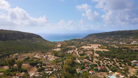 Drone-approaching-Greek-bay-passing-over-fields-and-farms