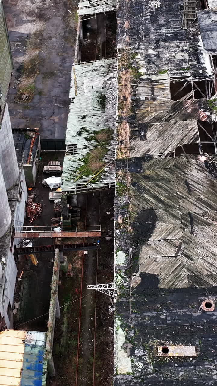 Holes in the roof of a warehouse in old abandoned chemical plant. Territory and buildings in decay. Aerial perspective. Vertical video