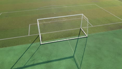 aerial view drone flying around an empty soccer goal, football field sunset