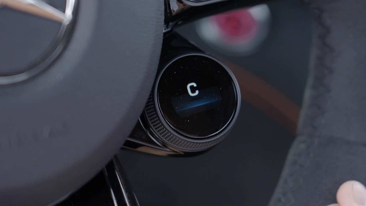 Close-Up of Hand Switching to Sport Mode on Steering Wheel Dial in Mercedes Car