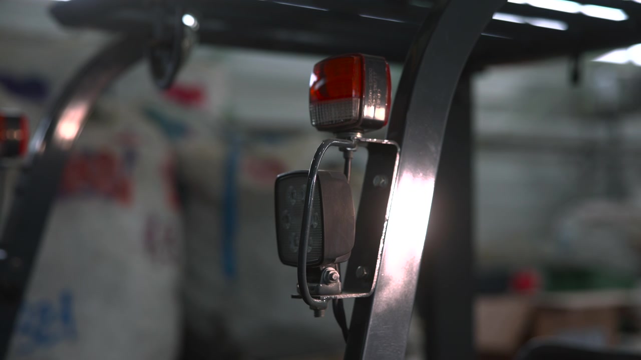 Primo piano della luce di avvertimento ambra del carrello elevatore, telaio metallico e specchio in un magazzino buio, contesto di ispezione di manutenzione