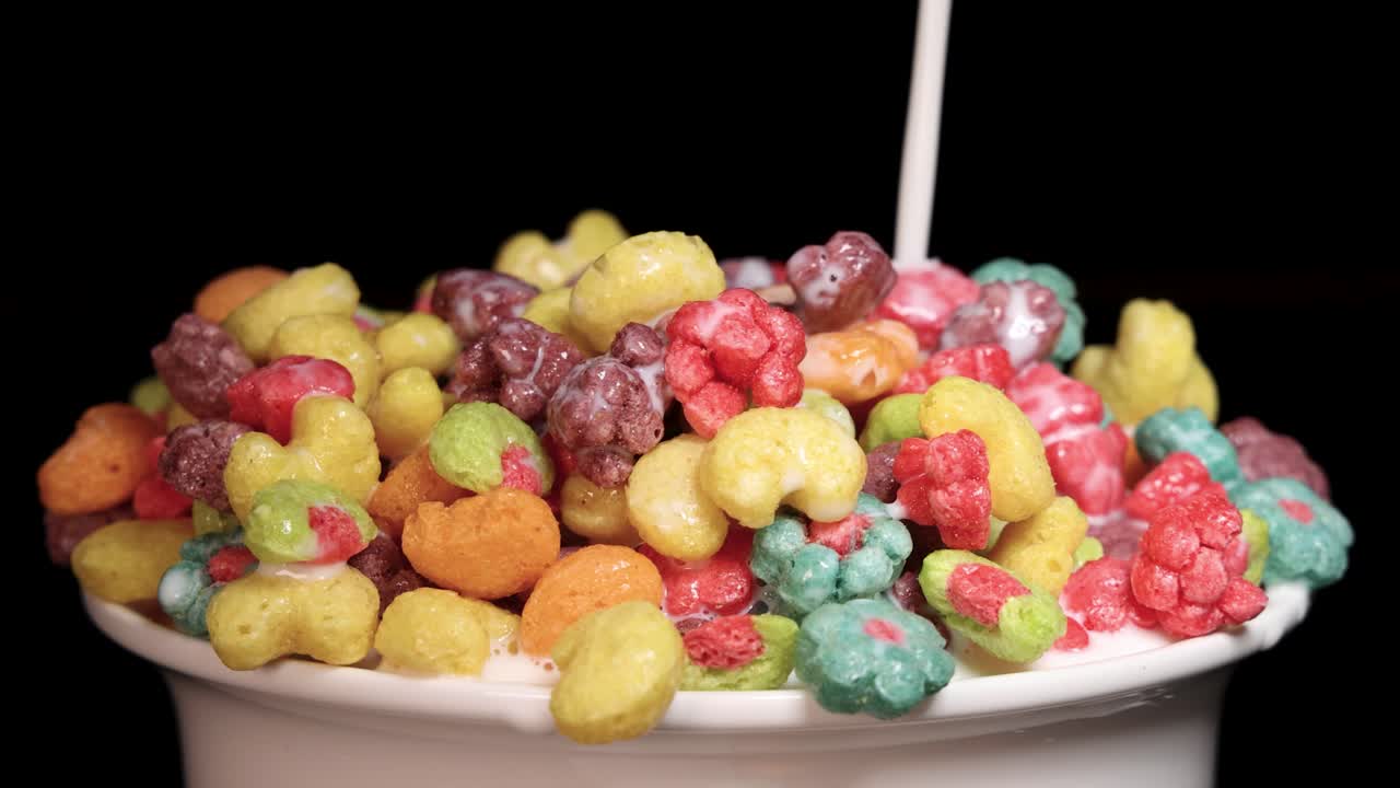 Vibrant cereal pieces in a bowl with milk pouring over them, creating a dynamic and colorful scene