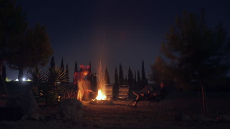 el lapso de tiempo muestra a un grupo de personas reunidas alrededor de una fogata con el brillante cielo nocturno arriba