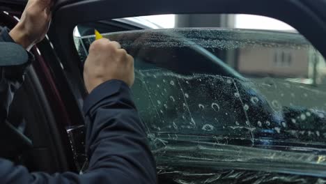 man washing car window with window cleaner - close up