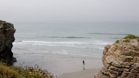 coastal scene with person walking on a misty beach