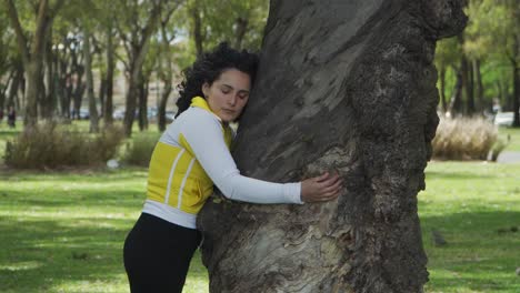 Gut-Aussehende-Junge-Brünette-Frau,-Die-Ihre-Augen-Schließt,-Während-Sie-Einen-Baum-Im-Wald-Von-Palermo-Umarmt