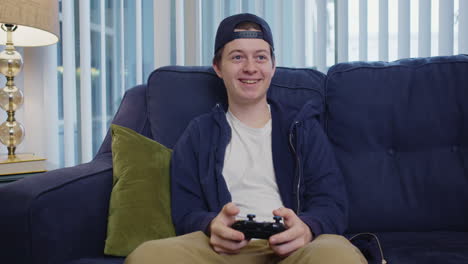 young man smiles and celebrates while playing video game