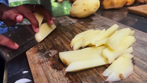primer plano de la mano con un cuchillo cortando patatas frescas