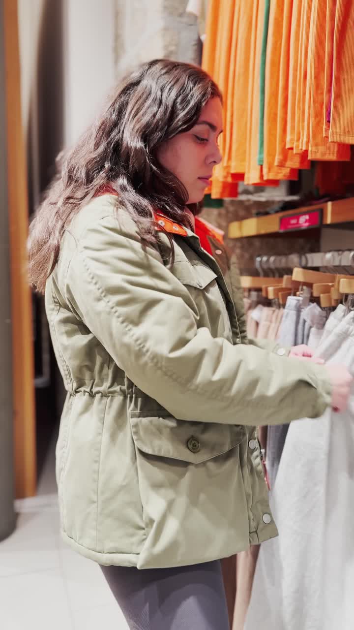 Giovane donna che sceglie i vestiti in un negozio di abbigliamento.