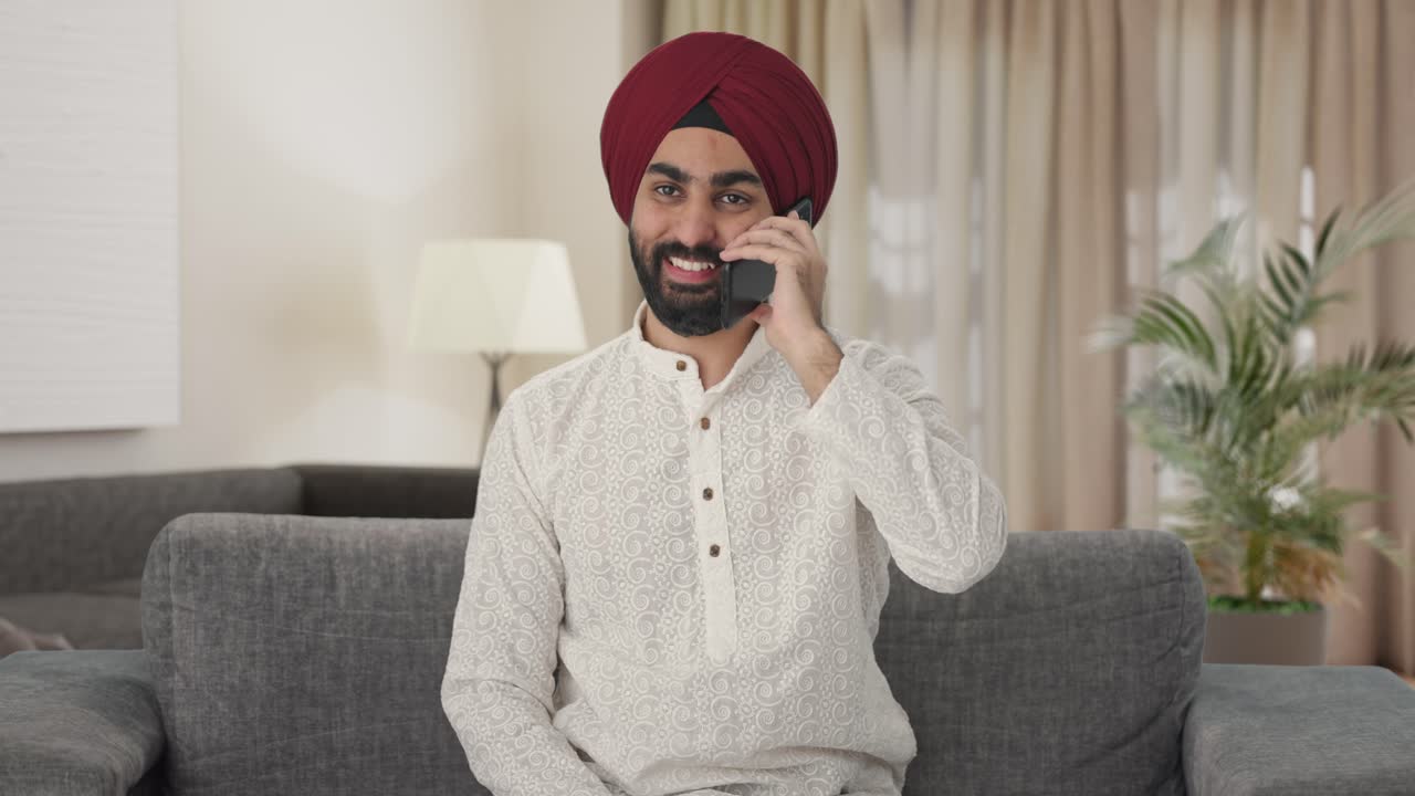 Uomo Sikh indiano felice che parla al telefono