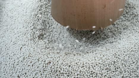 plastic pellets pouring from cardboard container