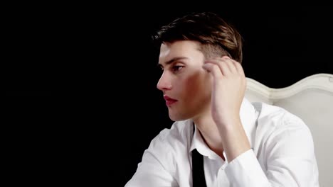 androgynous man posing against black background