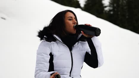 Girl in chilly Switzerland environment, open thermos bottle and drink warm tea