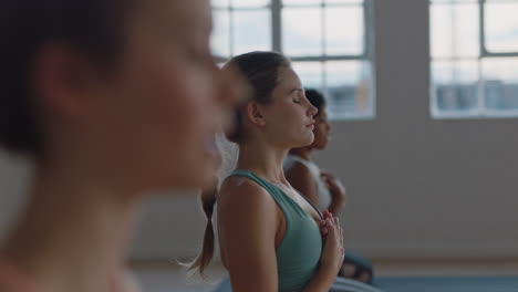 Hermosa-Mujer-Caucásica-En-Clase-De-Yoga-Practicando-Ejercicio-De-Atención-Plena-Con-Un-Grupo-De-Meditación-Disfrutando-De-Un-Estilo-De-Vida-Saludable-Entrenando-En-Un-Gimnasio-Al-Amanecer.