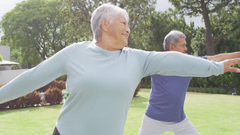 Happy-senior-diverse-couple-practicing-yoga-in-garden