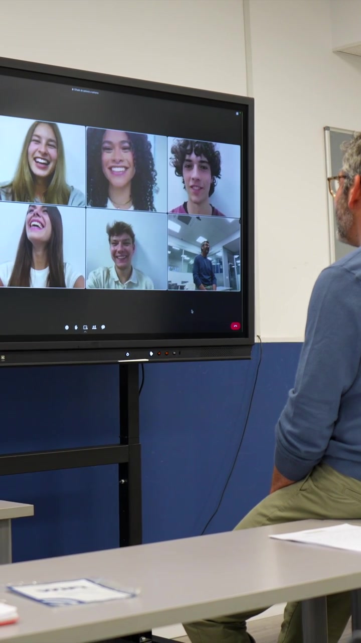 Teacher Leading a Virtual Class with Smiling Students on a Large Screen