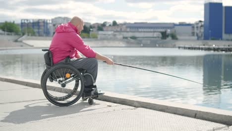 persona con discapacidad física que utiliza silla de ruedas para pescar en el muelle de pesca