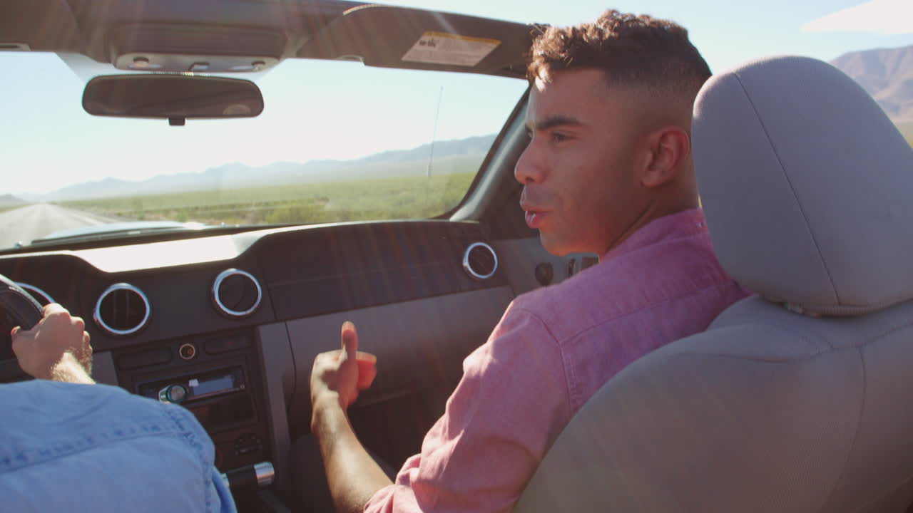 dos hombres en un coche descapotable conduciendo a lo largo de la carretera disparado en r3d