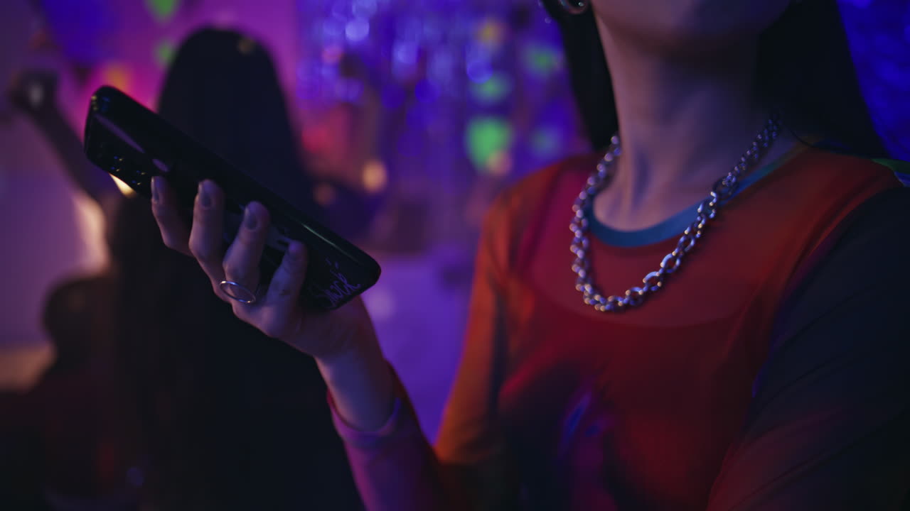 woman texting smartphone at vibrant neon nightclub closeup. Fashion girl